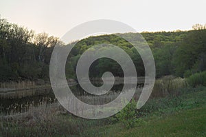 Picturesque spring landscape with hills overgrown with verdant forest and winding river at the foot hiding on a turning