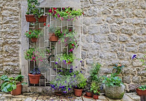 Picturesque stone wall in the streets of a preserved medieval Old town with colorful potted flowers in Budva, Montenegro