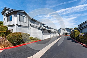 A picturesque street view of a row of colorful townhouses in a California community with cloudy sky in the background