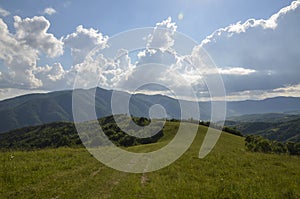 Picturesque sunny landscape of green mountain hills, forest, grassy meadow and cloudy sky. Carpathians Ukraine