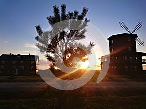 A picturesque sunset against a blue sky, houses and a mill