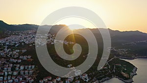 Picturesque sunset over coastal town. Sea bay and mountains with cityscape.