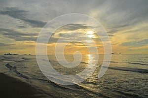 A picturesque tropical yellow coloured nimbostratus cloudy coastal sunrise seascape in a grey sky. Thailand