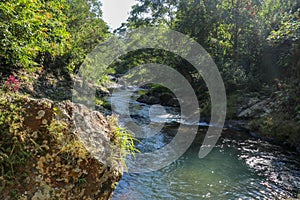 Picturesque valley in mountains and calm river. Boulders in the riverbed and rocks along the valley.