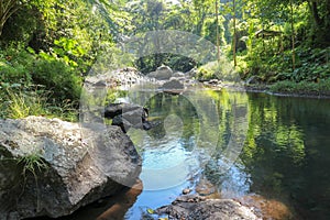 Picturesque valley in mountains and calm river. Boulders in the riverbed and rocks along the valley.