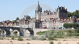 Picturesque view of ancient historic manor of Chateau de Gien rising above row of townhouses on bank of Loire river on