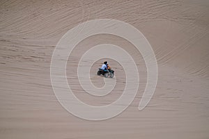 Picturesque view of ATV driving on sandy dunes and tire tracks on sand