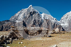 Picturesque view authentic tibetan habitation and stone fence in the Khumbu region in Nepal with majestic Taboche mountain 6501m