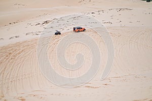 Picturesque view of big car driving on sandy dunes and tire tracks on sand