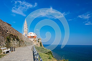 Scenic view of coastline of Adriatic sea with alley along Piran old city walls and cathedral on background, Slovenia photo