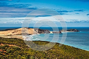 Picturesque view of the coastline of a vast ocean, featuring a sandy beach at the forefront