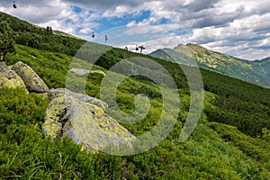 Malebný pohľad na trávnatý horský svah s lanovkou v diaľke. Nízke Tatry.