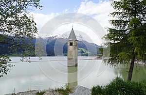 scenic view of lake Resia and sunken church steeple of Lago di Resia in Curon region (Vinschgau, South Tyrol, Italy) photo