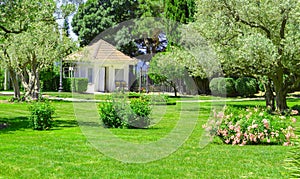 Picturesque view of the Mediterranean landscape with a beautiful lawn, a small farmhouse and olive and cypress trees