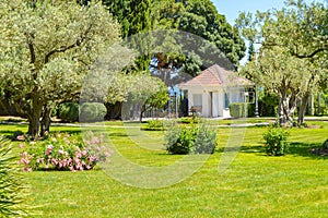 Picturesque view of the Mediterranean landscape with a beautiful lawn, a small farmhouse and olive and cypress trees