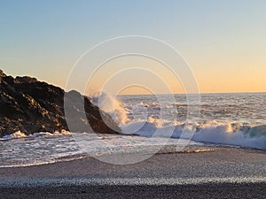 Picturesque view of a ocean waves crashing rock formation at the coastline during a sunset