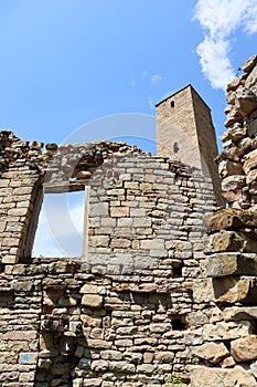Picturesque view of old stone battle tower with the window of ruined house in abandoned village