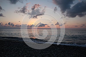 Picturesque view of pebble beach and sea at sunset