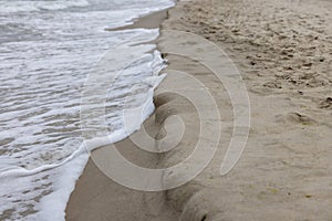 Picturesque view of the sandy beach of the Baltic Sea, foamy water flowing into the sand, Miedzyzdroje, Poland