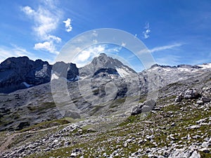 Picturesque view of snowy mountain slopes with rocky peaks and blue sky. Tourist scenic landscape