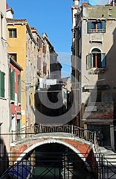 Picturesque view of Venice Italy showing a bridge laundry hanging out and a navigable canal between houses