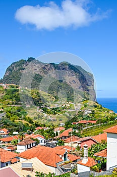 Picturesque village Porto da Cruz in Madeira island, Portugal. Houses on the green hills, rock formation, cliff by the Atlantic