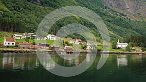 A picturesque village with traditional wooden houses on the shore of the fjord in Norway. View from a floating cruise
