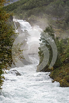 Picturesque waterfall cascades over a rocky cliff face surrounded by lush greenery