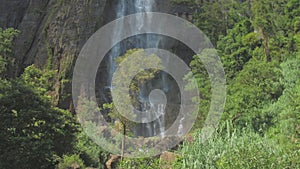 Picturesque waterfall from high rocky cliff with green trees