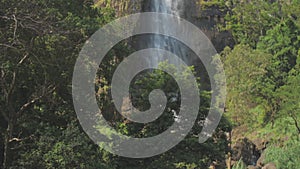 Picturesque waterfall from high rocky cliff with green trees