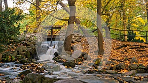 Picturesque waterfall in the Oliwa Park in autumnal scenery.