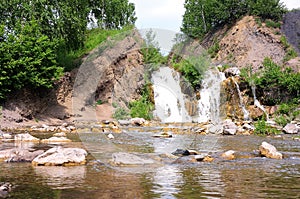 A picturesque waterfall with rocky cliffs and a shallow river flowing from it