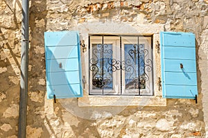 Picturesque window with blue shutters white limestone wall Croatia, Balkans