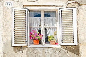 Picturesque window , shutters, colorful flowers against a white limestone wall