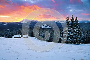 Picturesque winter landscape with huts, snowy mountains.