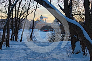 Picturesque winter landscape view of Holy Intercession Cathedral Ukrainian Orthodox Church in tree trunks border during sunset.