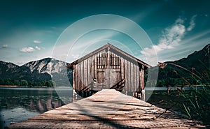 Picturesque wooden fishing shack situated on a dock overlooking a serene lake in Chiemsee, Germany