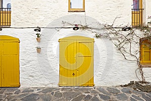 Picturesque yellow doors over a white facade. Cadaques, Catalonia. Spain