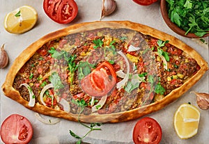 Pide is a Turkish boat-shaped flatbread stuffed with minced lamb and beef, with spices and herbs. Wooden table, top view, flat lay