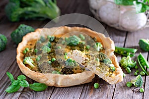 Pie with broccoli and green peas on a wooden board on the table