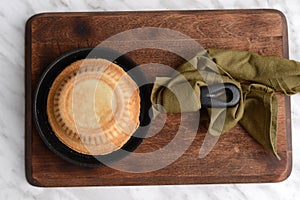 Pie in cast iron skillet on wood cutting board