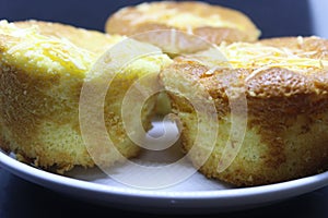 Pie with chesee on a white plate. Sponge cake with black background.