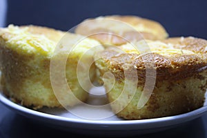 Pie with chesee on a white plate. Sponge cake with black background.