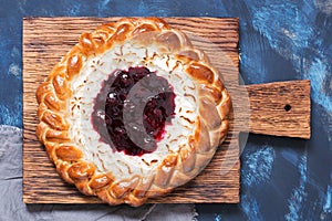 Pie with cottage cheese and berry jam close-up on a cutting board, top view.