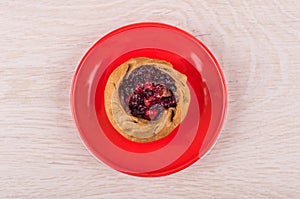 Pie with cowberries in red saucer on wooden table