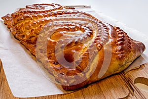 Pie with fresh meat on a wooden table close-up. Homemade cakes. Traditional Russian and Ukrainian cuisine.