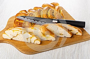 Pie with lemon jam, knife, slices of pie on cutting board on wooden table