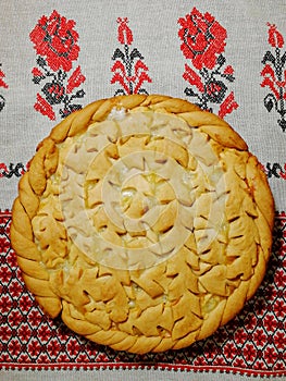 Pie with a pattern of dough on an embroidered towel.