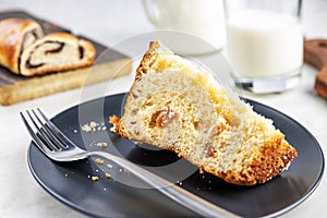 Pie with poppy seeds sliced into pieces, on wooden boards and in a dish, a glass and a jug with milk, selective focus
