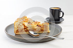 Piece of an apple pie with ice cream and cup of coffee espresso on white wooden table